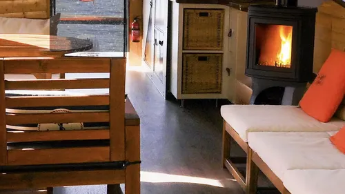 Wooden table and chairs, fireplace lights, cozy interior.