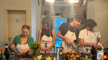 Vier Personen kochen gemeinsam in einer modernen Küche.