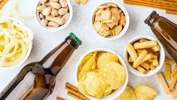 Flaschen und Snacks liegen auf einem hellen Tisch.