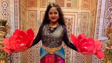 Woman holding red lotus flowers, decorated background with statues.