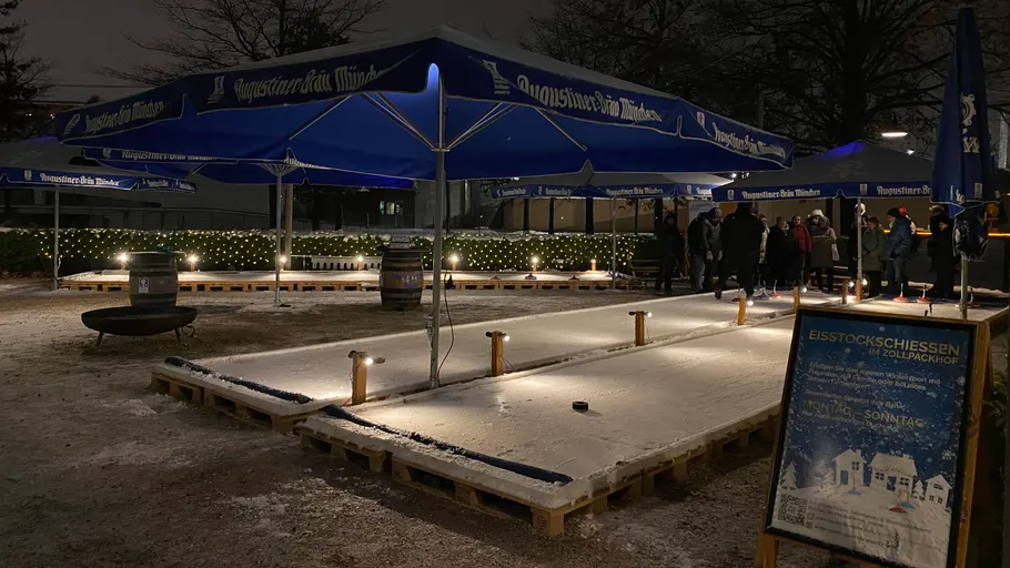 Outdoor ice rink with people and umbrellas.