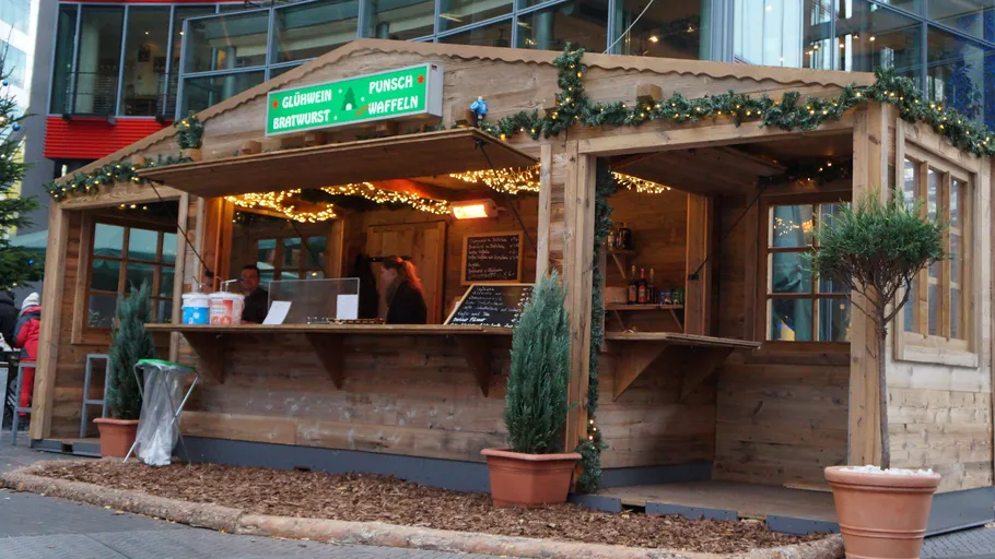 Wooden Christmas market stall with lights and menu.