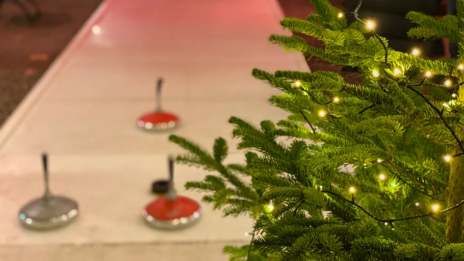 Christmas tree with lights near curling stones.