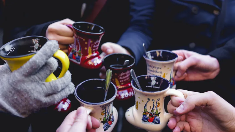 People holding colorful mugs with spoons, outdoors.
