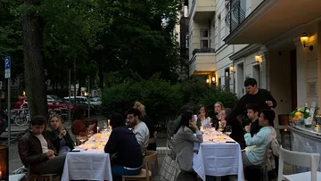 Leute, die draußen an einem langen Tisch essen.