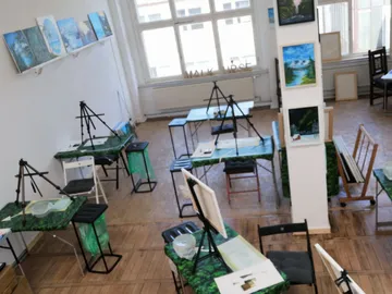 Leere Malwerkstatt mit Staffeleien und Tischen.