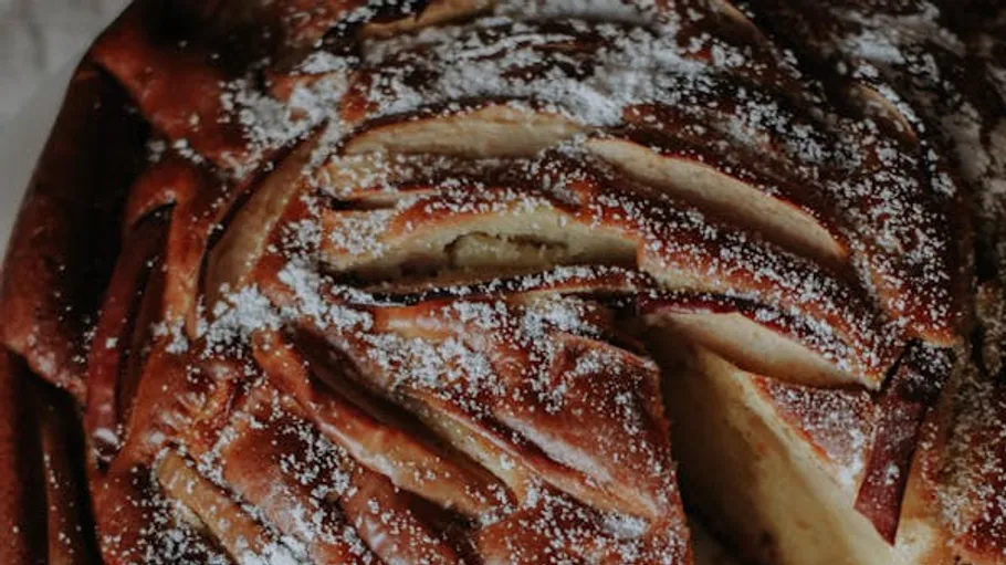 Apple cake, freshly baked, dusted with powdered sugar.