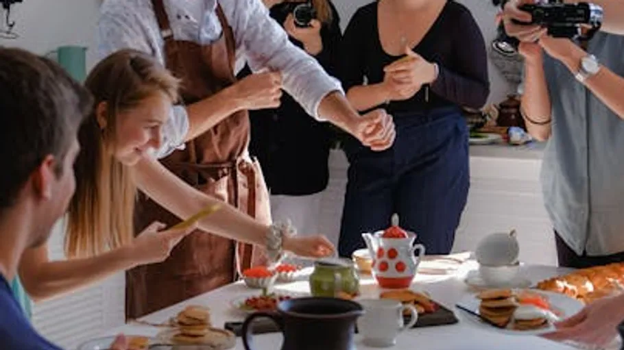 One person serves food while others watch and film.