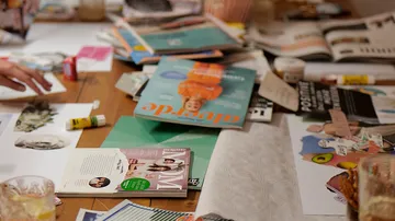Zeitschriften und Materialien liegen auf einem Tisch verstreut.