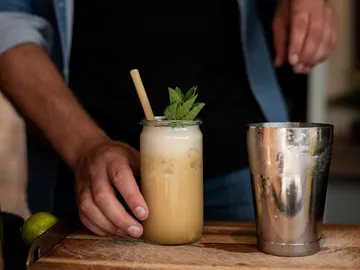 Glass with drink and mint, hand grabs it