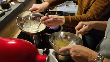 Two people stir in bowls on a work surface.