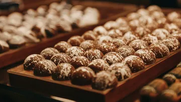 Chocolate balls lie neatly on a wooden tray.