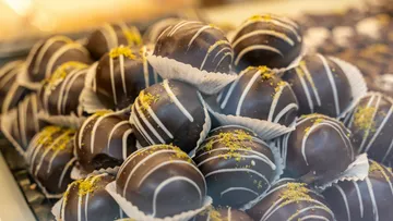 Chocolate balls are stacked with icing and nuts.
