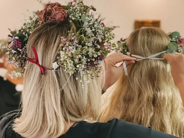 Frau mit Blütenkranz bindet Ribbons in langes Haar.