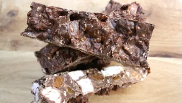 Chocolate bars are piled up on a wooden table.