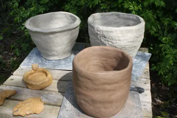 Drei Tontöpfe trocknen draußen auf einem Tisch.