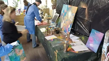 Farbenfrohe Kunstwerke entstehen auf einem Tisch im Atelier.