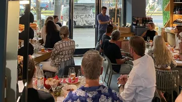 Gruppe von Personen hört einem Redner in einem Restaurant zu.