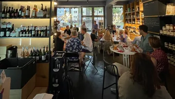 Menschen essen und trinken in einer Weinbar mit Regalen.