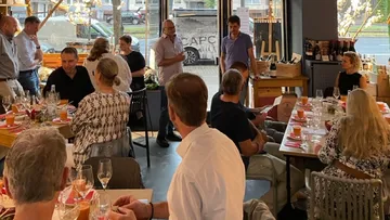 Menschen diskutieren entspannt in einem Restaurant mit Tischen.