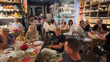 Gruppengespräch in einem Restaurant mit Weinregalen im Hintergrund.