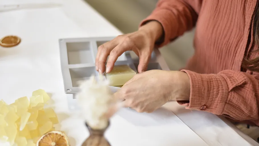 Hand grabs soap and places it in shape on the table.