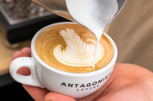 Eine Kaffeetasse erhält eine dekorative Milchschaumgarnitur.