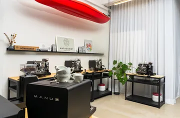 Coffee equipment is placed on tables surrounded by bright rooms.