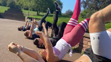 Group of people do outdoor exercises on the ground.