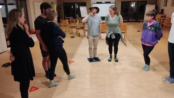 Group game, participants stand, one explains an exercise.