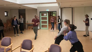 Group dance with people in a bright room.