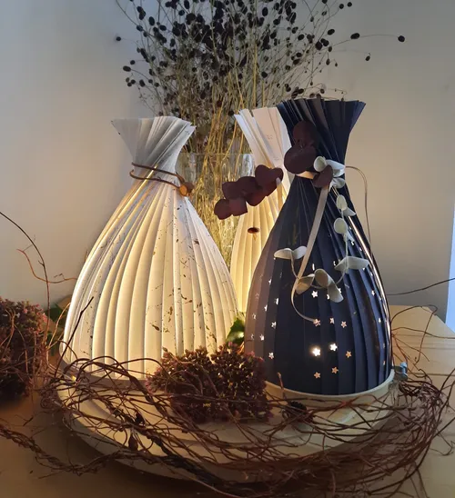 Folded paper lanterns glowing on a table.