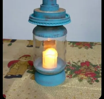 Blaue Laterne mit Kerze auf Tischdecke.