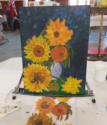 A painting of sunflowers is on a table.