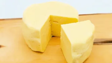 Käseblock auf Holzbrett, geteilt in zwei Stücke.