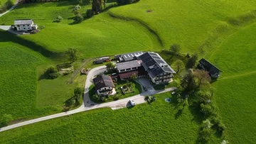Landsitz mit mehreren Gebäuden umgeben von grünen Wiesen.