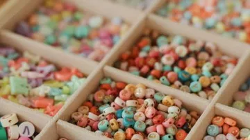 Colourful beads lie messy in cardboard compartments.