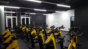 Gelbe Heimtrainer, aufgestellt in einem dunklen Fitnessstudio.