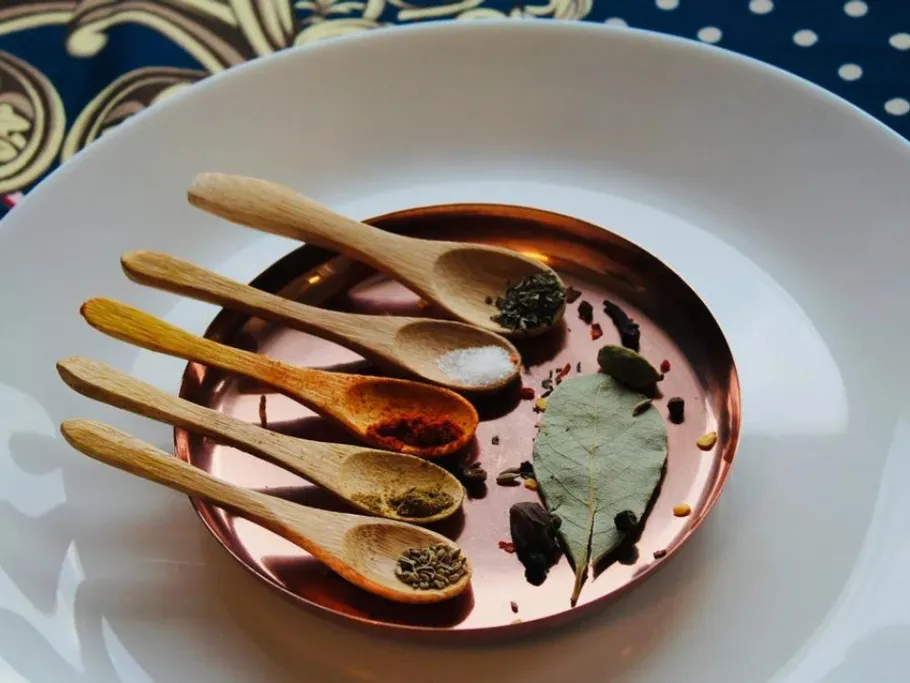 Wooden spoons with spices arranged on a round plate.