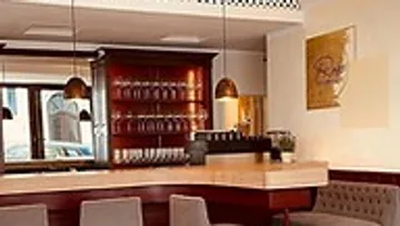 Bar with wooden bar, glasses and cozy seats.