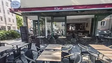 Tische und Stühle stehen vor einem Restaurant in der Stadt.