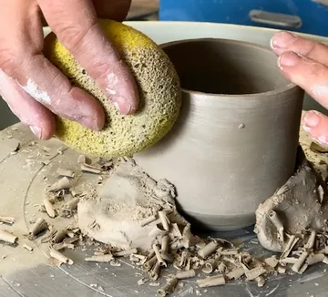 Clay pot is worked with a sponge, in workshop.