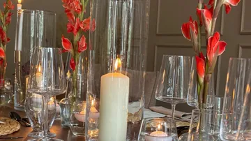 Glasvasen und Kerze dekorieren eleganten Tisch mit Blumen.