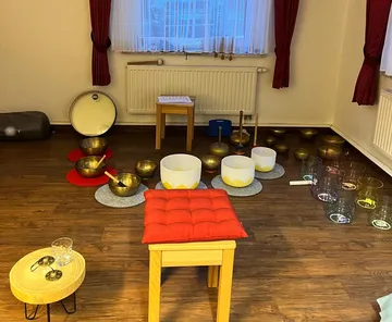 Singing and singing bowls stand on a wooden floor in a room.
