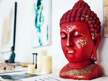 Red Buddha head on a table surrounded by candles and art