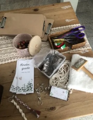 Bastelmaterialien liegen auf einem Holztisch, alles organisiert.