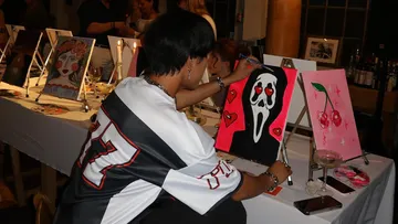 Person paints a picture with a black background and hearts.