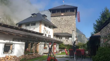 Steinerne Burg umgeben von Gebäuden und Natur.