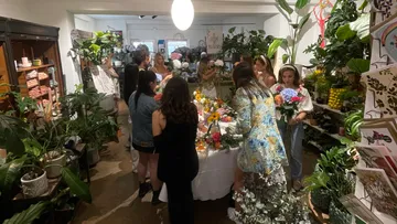 Blumenladen: Menschen arrangieren Blumen in einem lebhaften Raum.