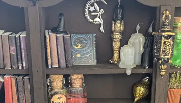 Shelf decorated with magic books, vials and candles.
